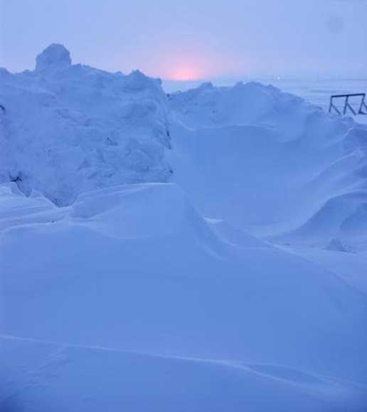 An early warm spell caused near shore ice to buckle and rise.  The light from the sun is just visible.